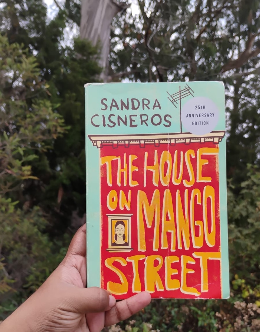 hand holding a copy of the house on the mango street by sandra cisneros